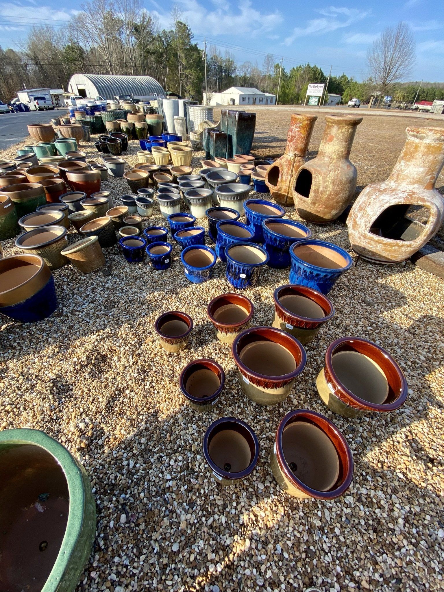 A bunch of pots and vases are sitting on top of a pile of gravel.