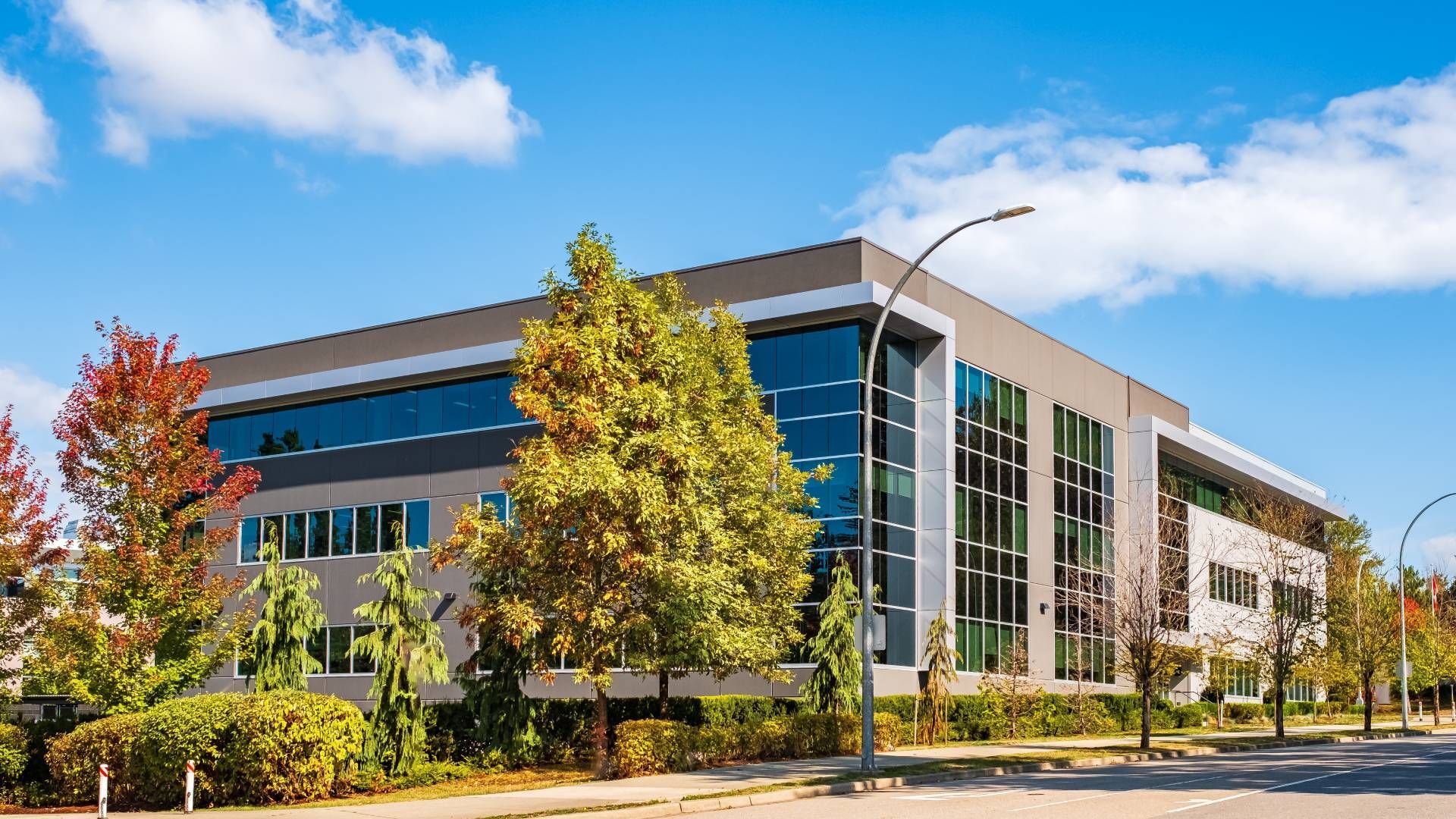 A large building with a lot of windows is surrounded by trees and bushes.