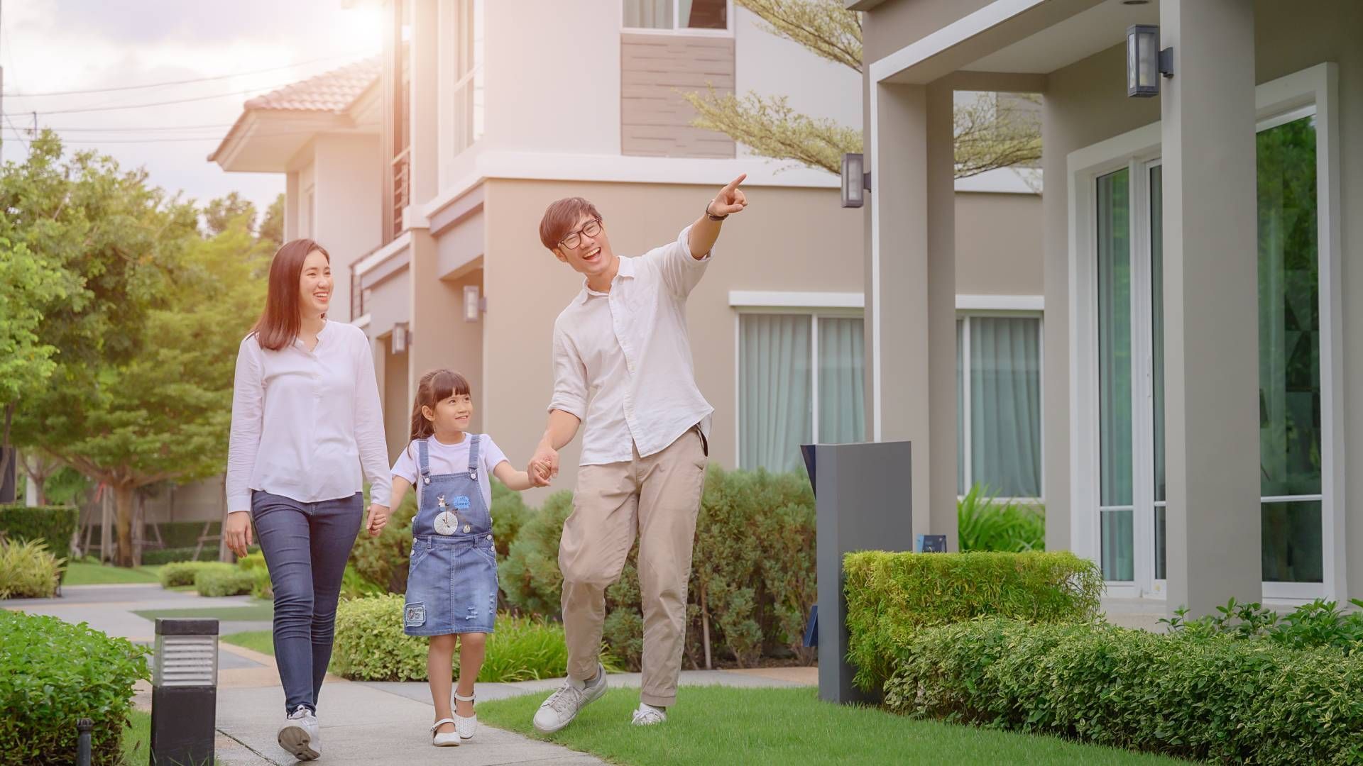 A family is walking down a sidewalk in front of a house.