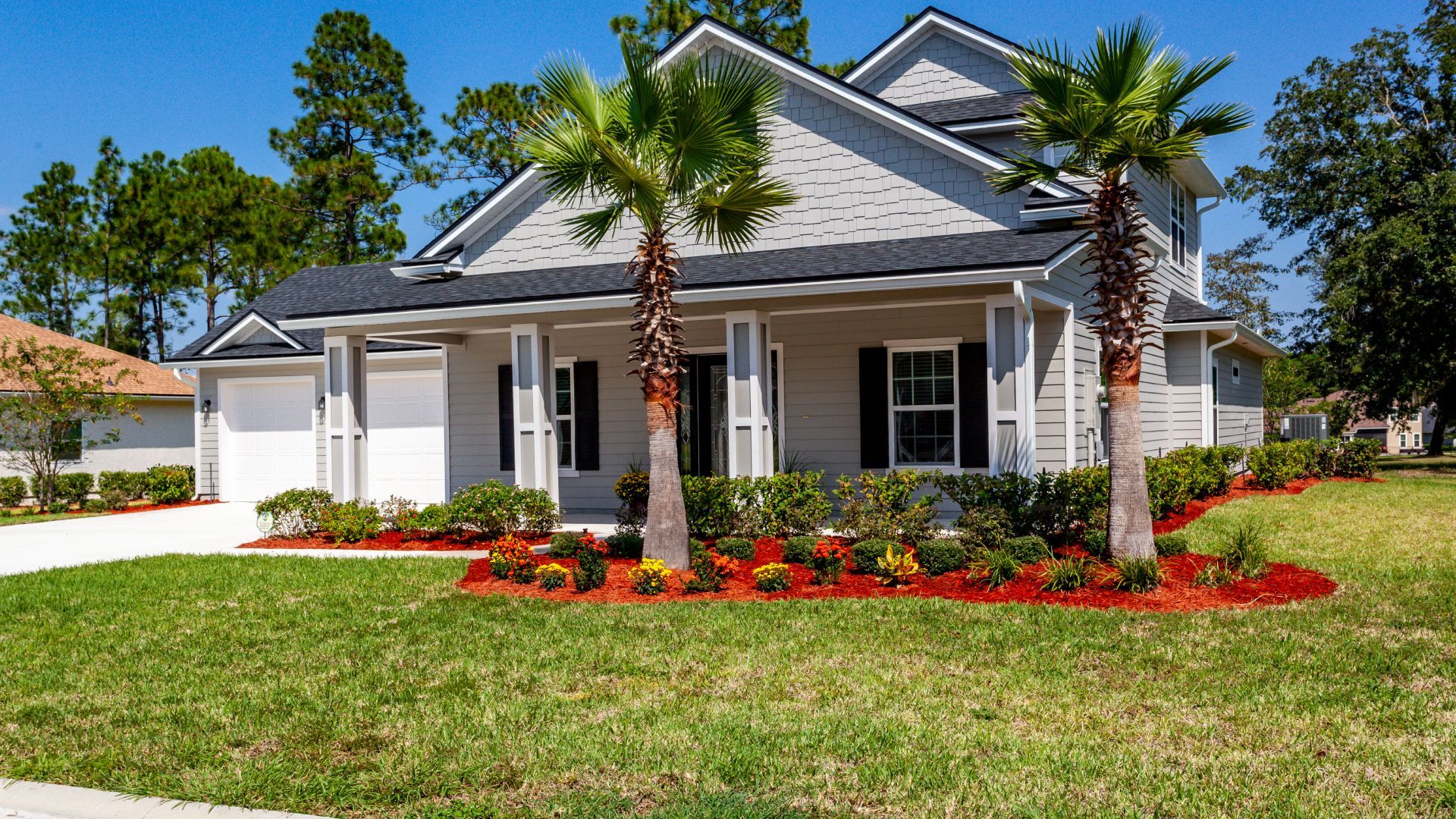 A large white house with a brown roof is surrounded by trees