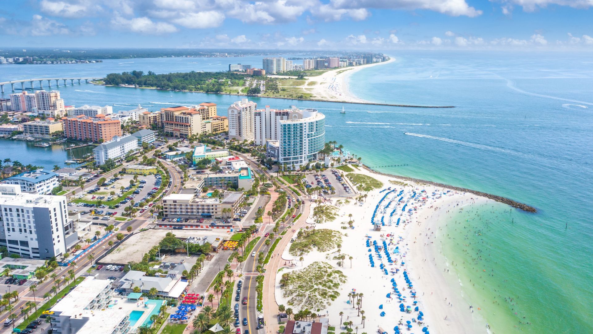 An aerial view of a city with a beach in the foreground and the ocean in the background.