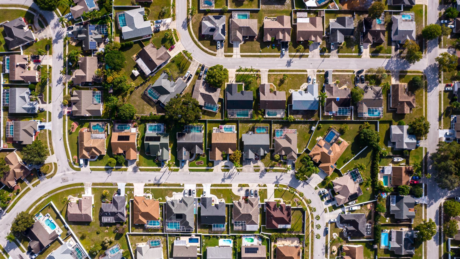 A man is standing in front of a house with a for sale sign.