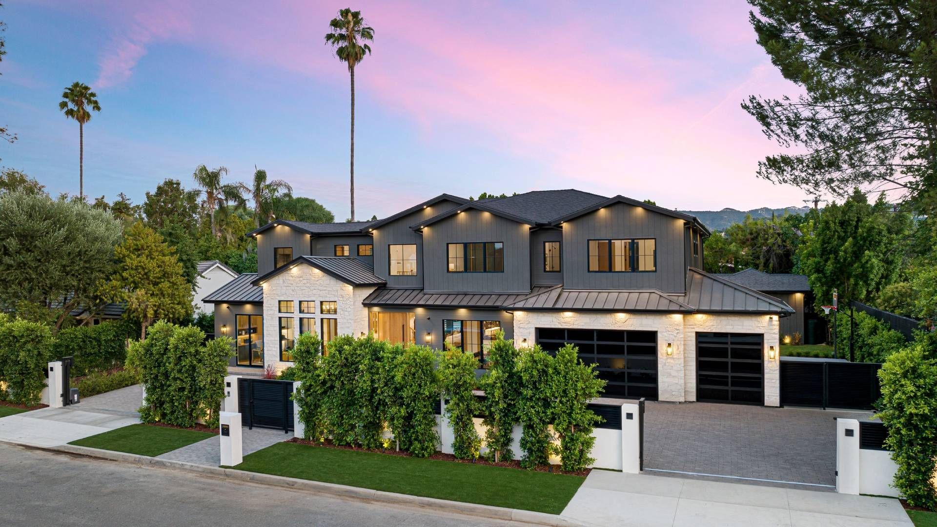 A large house is sitting on top of a lush green hillside surrounded by palm trees.