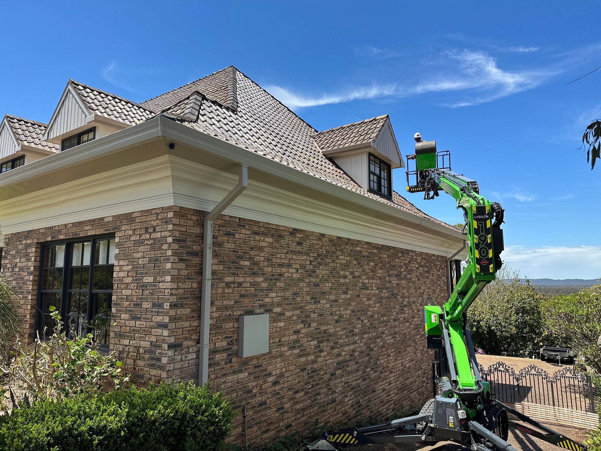 Green  Aerial Lift Is Parked Next To A House— High Work Services In Cessnock, NSW