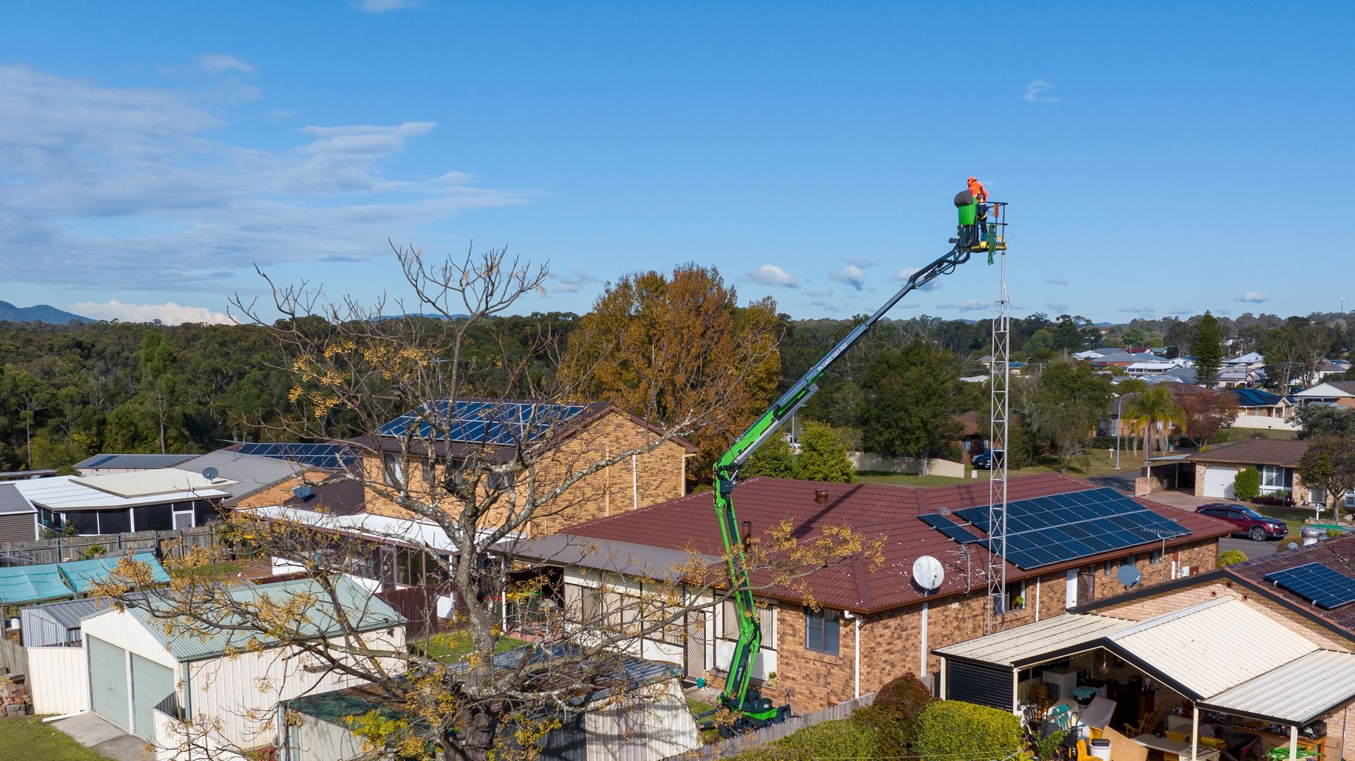 A Worker in a Cherry Picker Over a House — High Work Services in Maitland, NSW