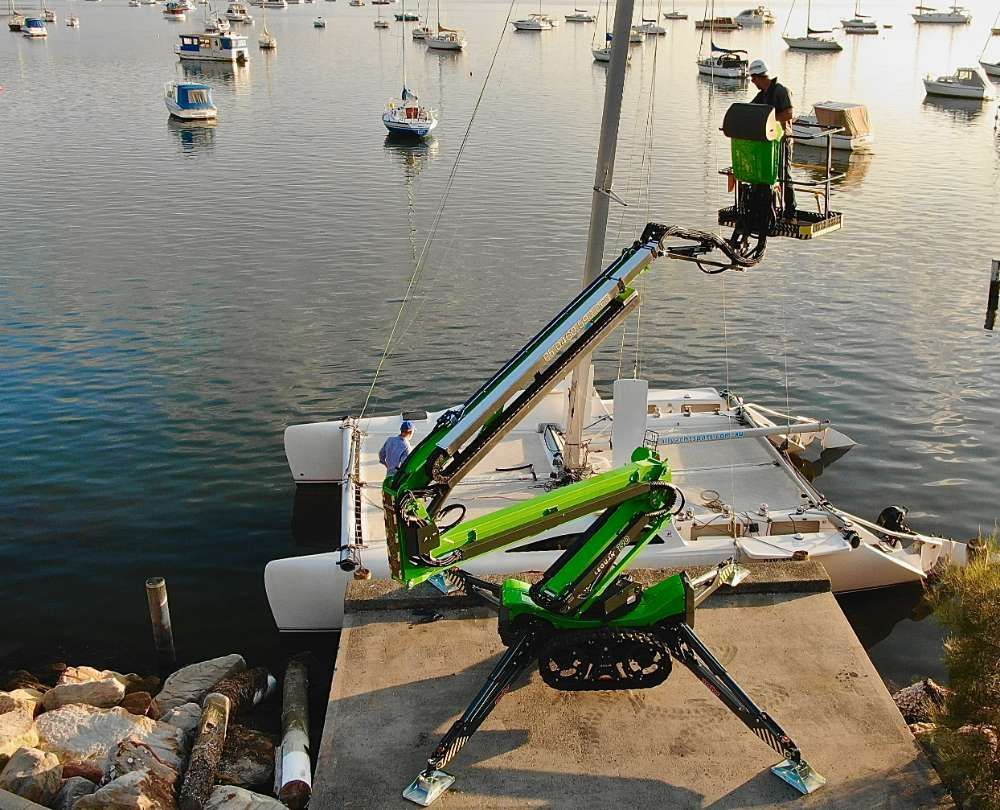 A Green Crane Is Sitting Next To A Boat In The Water — High Work Services in Maitland, NSW
