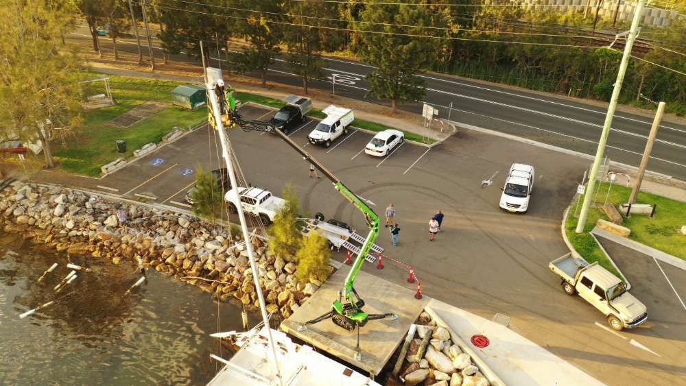 An Aerial View Of A Crane In A Parking Lot Next To A Body Of Water — High Work Services in Maitland, NSW
