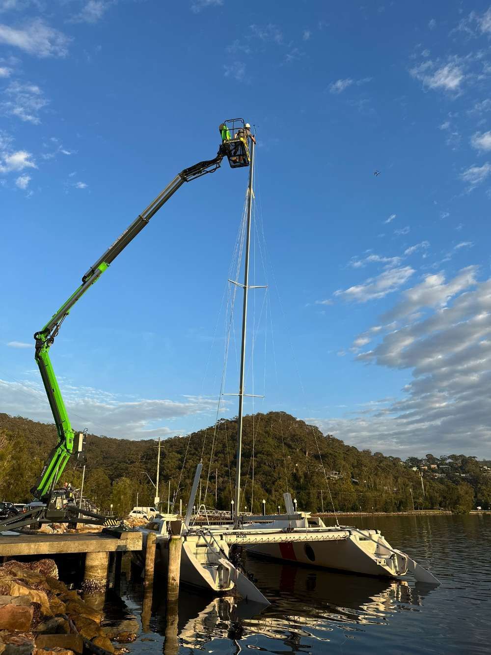 A Crane Is Lifting A Sailboat Into The Water — High Work Services in Maitland, NSW