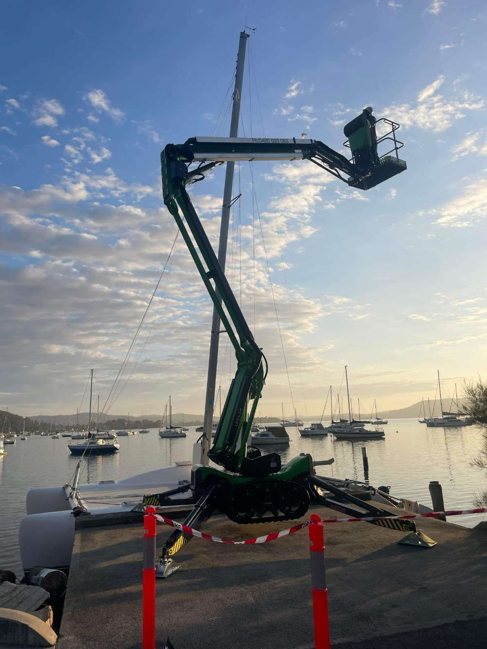 A Crane Is Sitting On A Trailer Next To A Body Of Water — High Work Services in Maitland, NSW