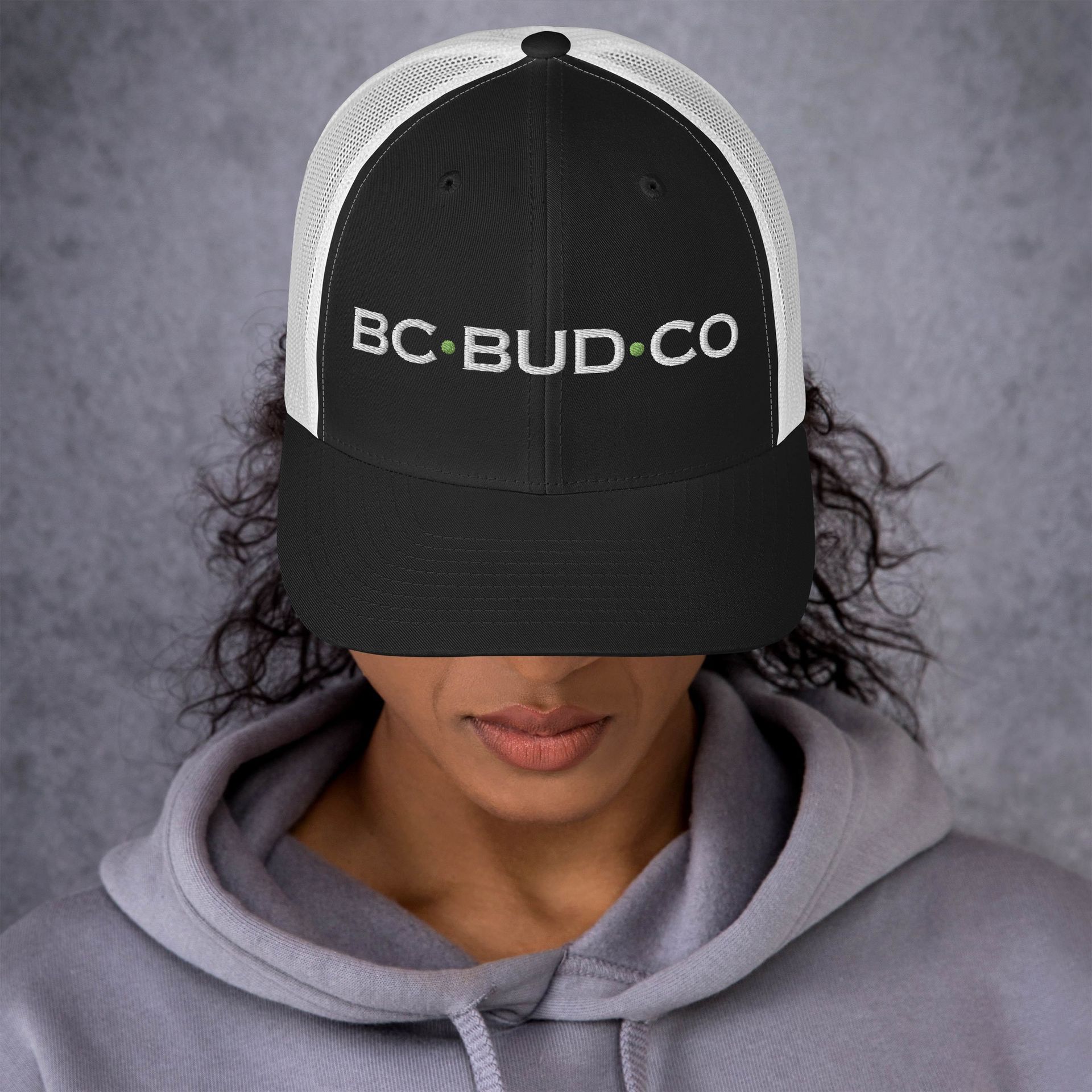 A woman wearing a black hat that says bud co on it