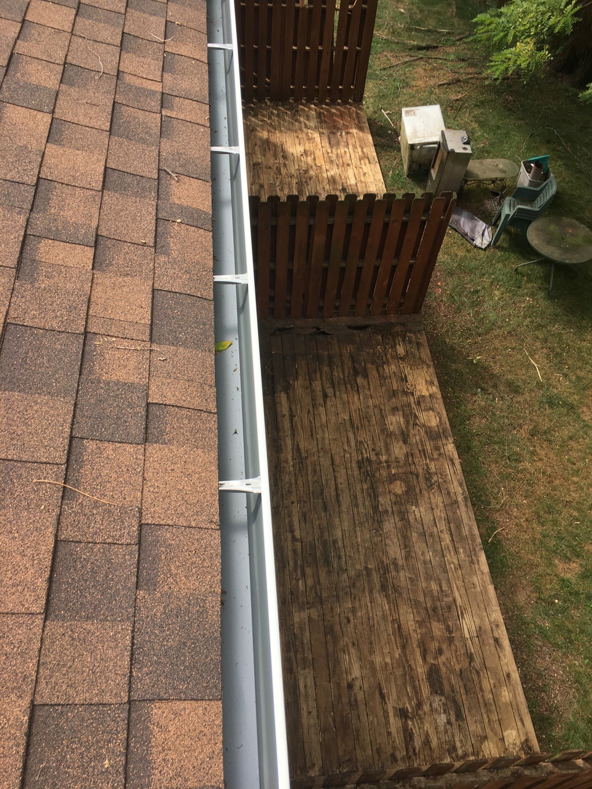 An aerial view of a gutter on a roof next to a wooden fence.