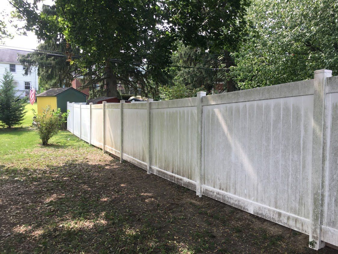 A white fence is sitting in the middle of a lush green yard.