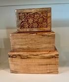 Three wooden boxes stacked, the top box carved with floral details.