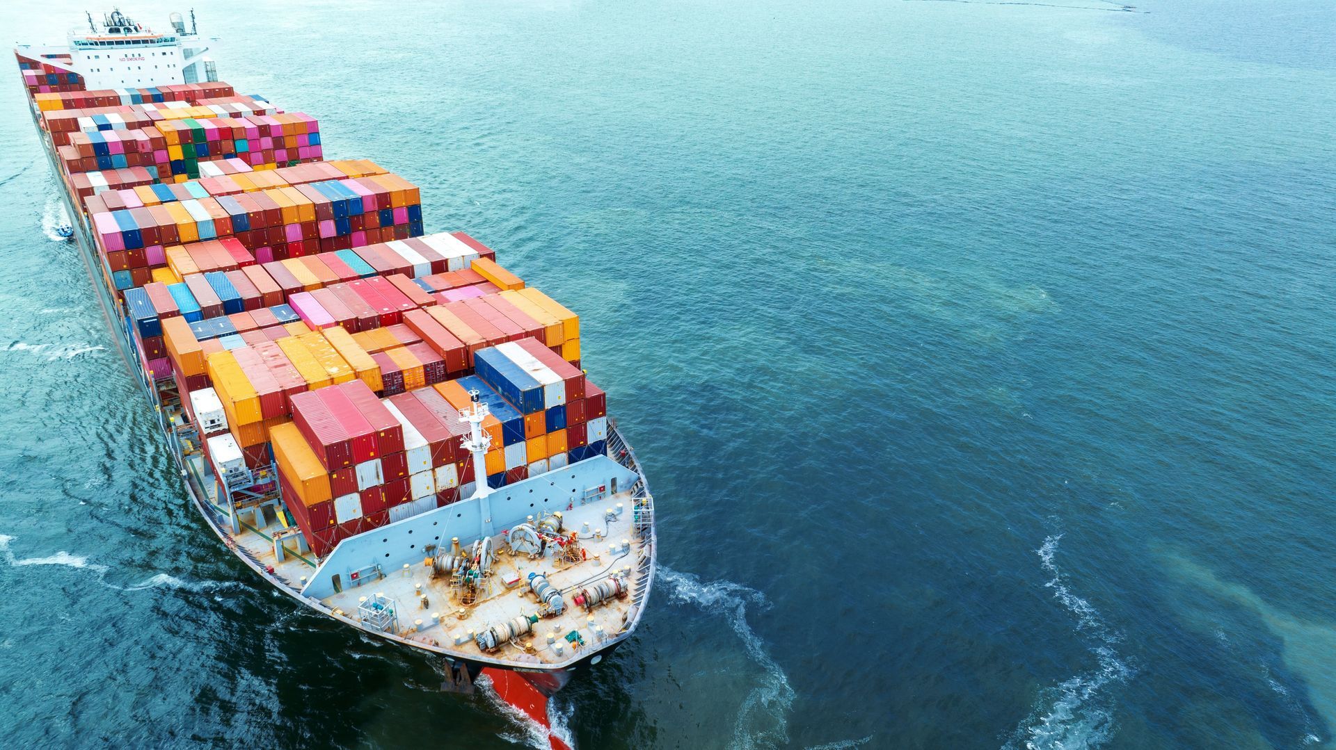Cargo ship carrying colorful shipping containers on the ocean.