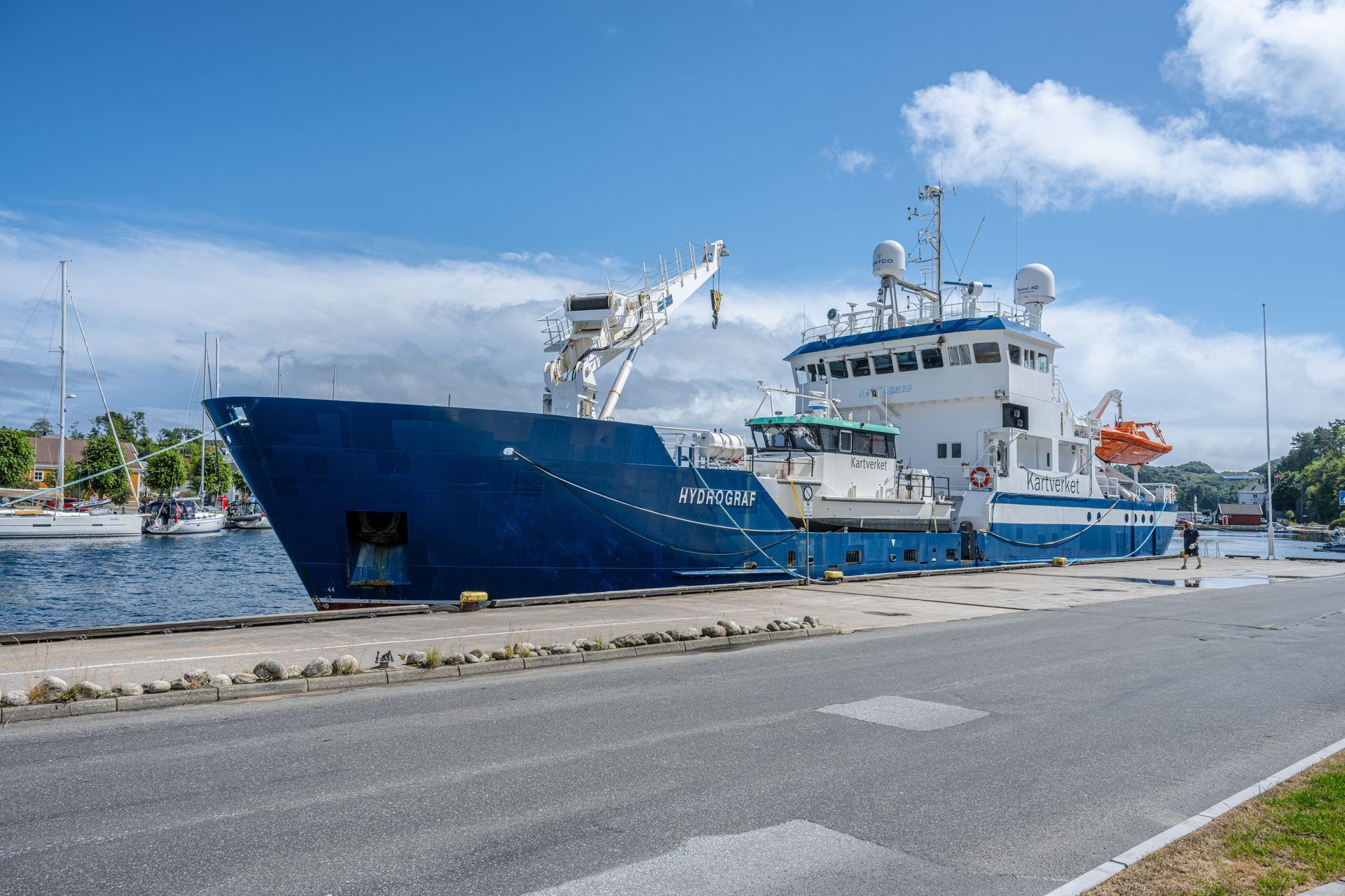 Blue research vessel docked at a harbor on a sunny day.