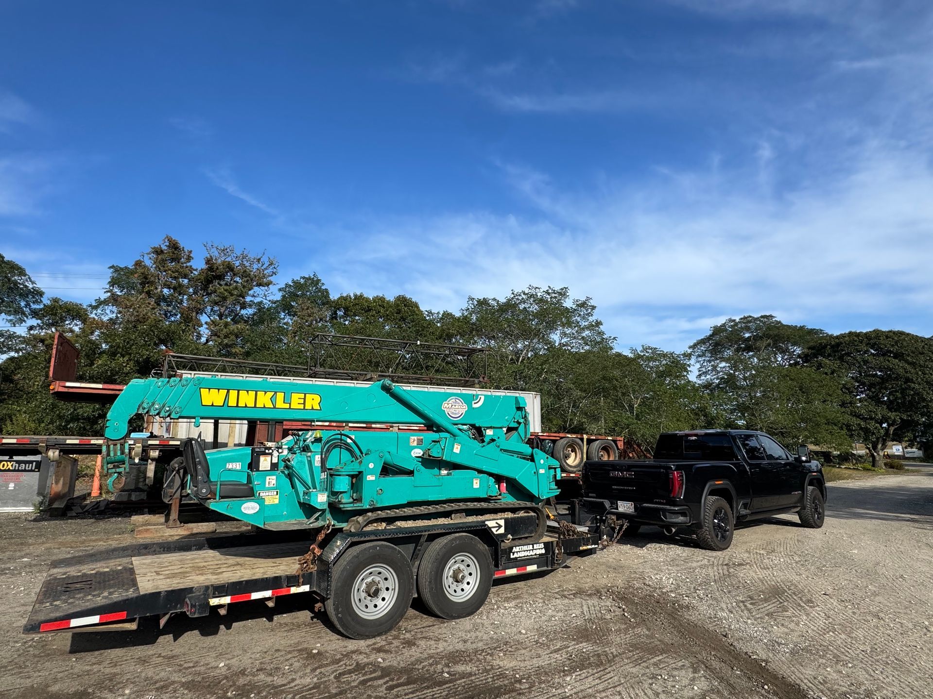 A yellow crane on a construction site lifting a precast concrete slab between vertical pillars under a clear blue sky.
