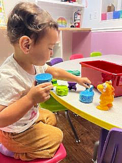 A young child plays with colorful toys at a table indoors.