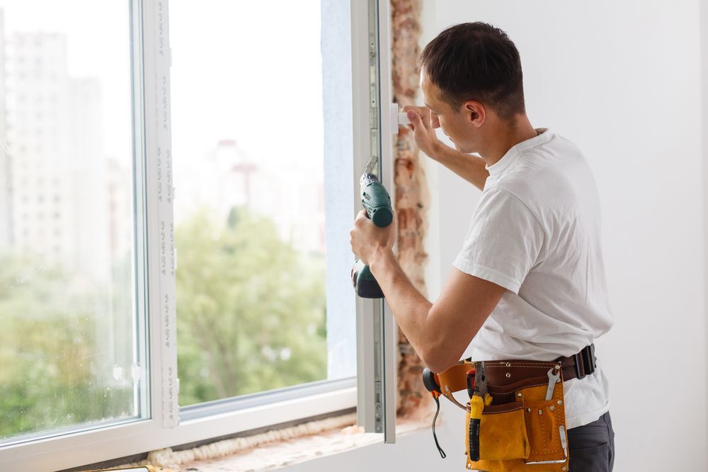 Man Installs a Window, Using a Drill, Wearing a Tool Belt — Southside Glass & Aluminium in Tablelands, QLD