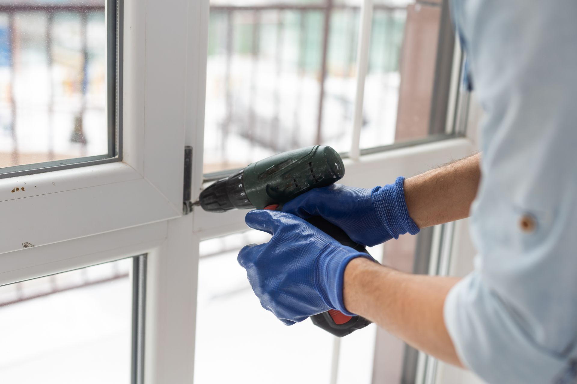 Person Wearing Blue Gloves Using a Drill to Install a Window — Southside Glass & Aluminium in Gordonvale, QLD