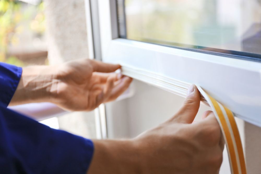 Person Applying Weather Stripping to a White Window Frame — Southside Glass & Aluminium in Palm Cove, QLD