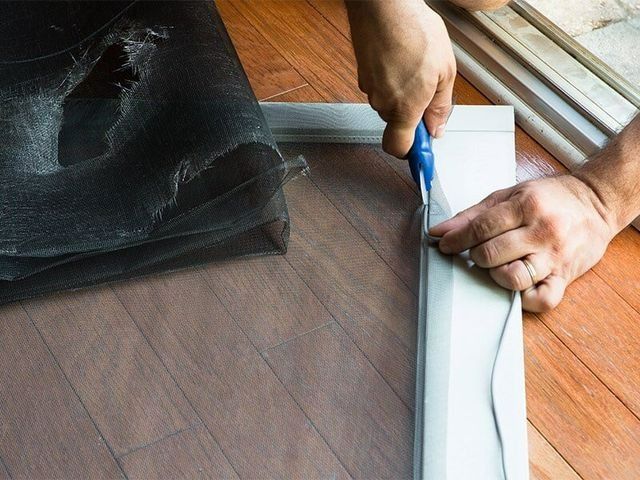 A Person Is Cutting A Mosquito Screen With Scissors — Southside Glass & Aluminium In Bentley Park, QLD 