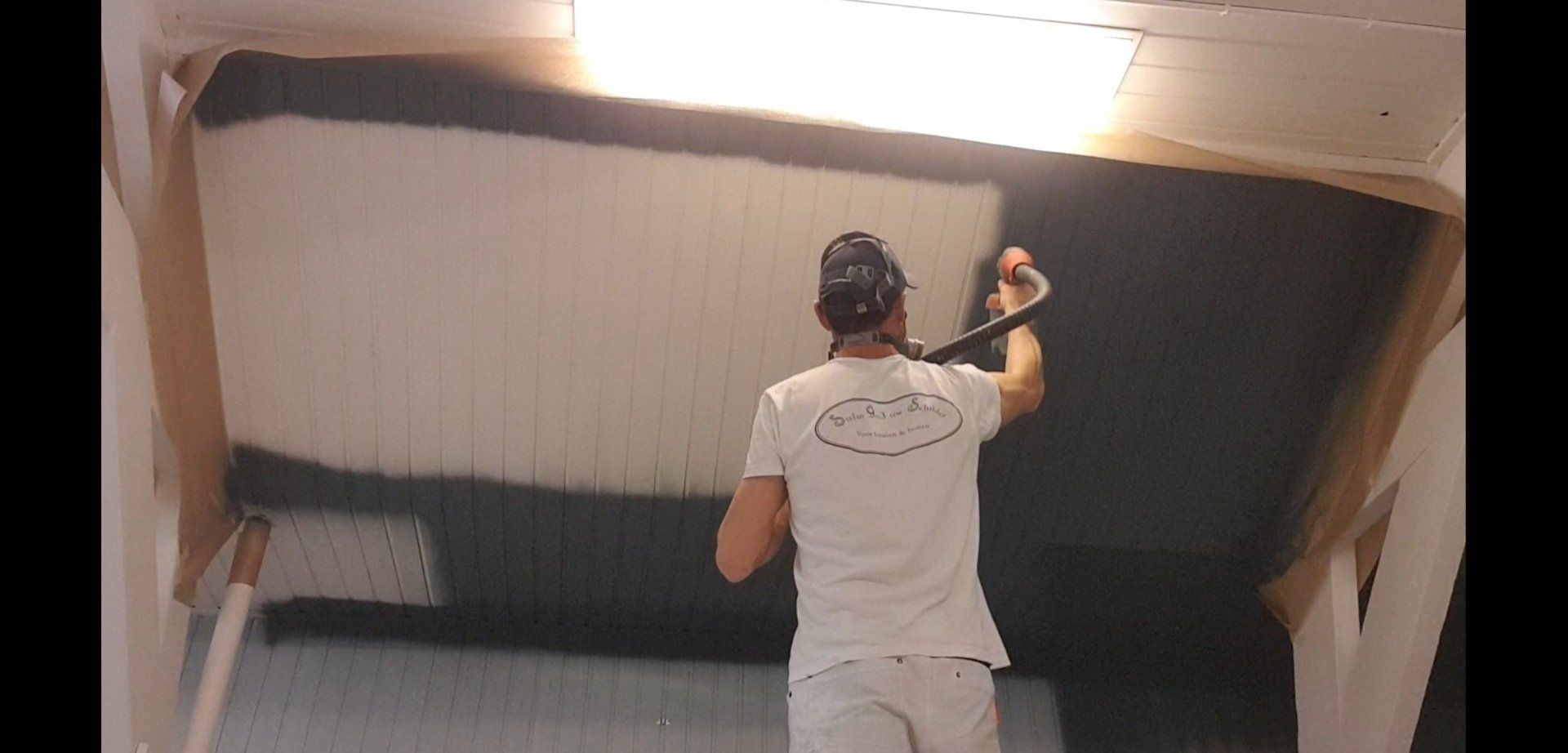 Stefan Godrie spuit donker blauwe verf op een witte muur.