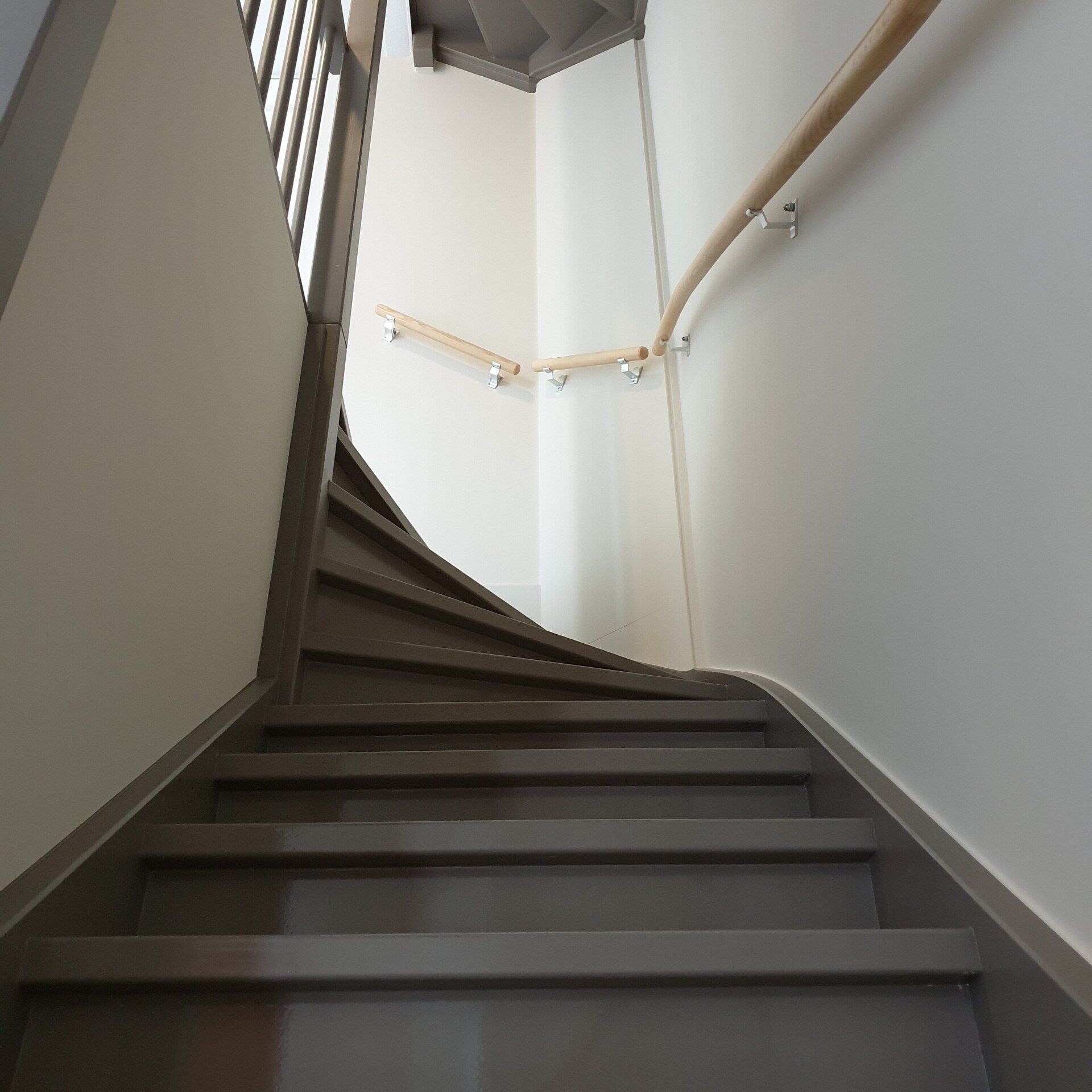 Een trap met grijze treden en crème afgewerkte wanden.