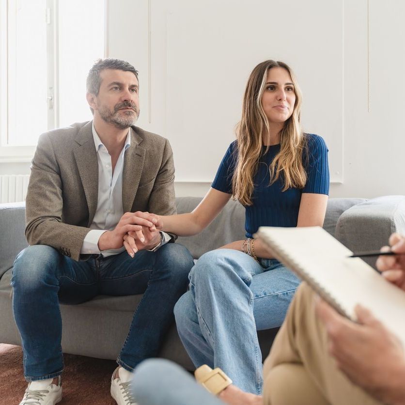 Un hombre y una mujer están sentados en un sofá hablando con un consejero.