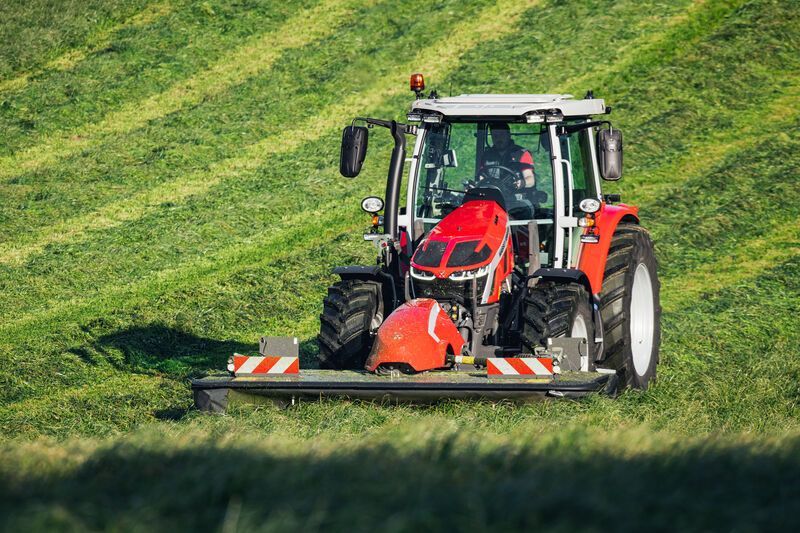 Red Massey Ferguson tractor on a grassy path with a scenic view.