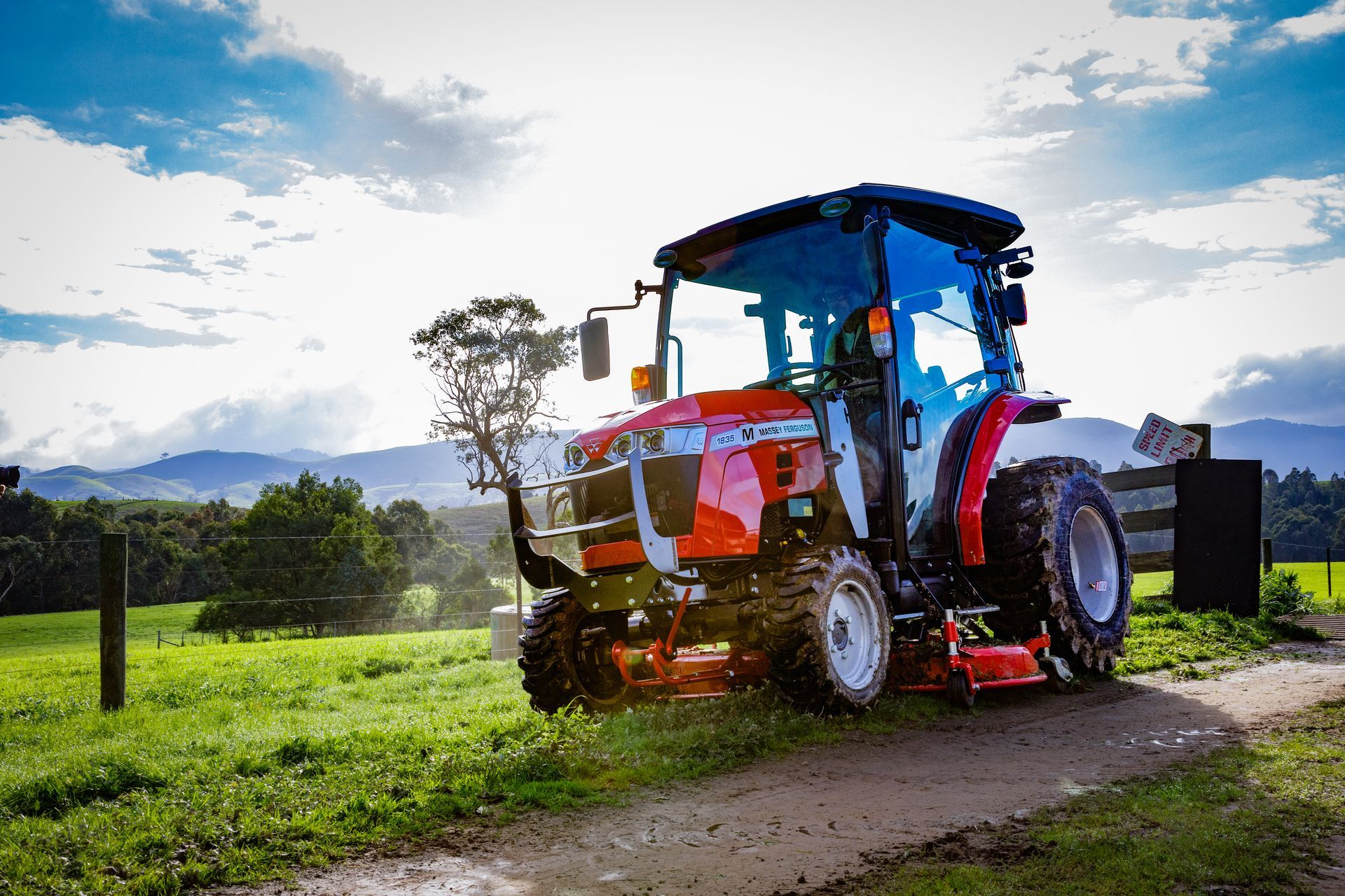 Red Massey Ferguson tractor on a grassy path with a scenic view.