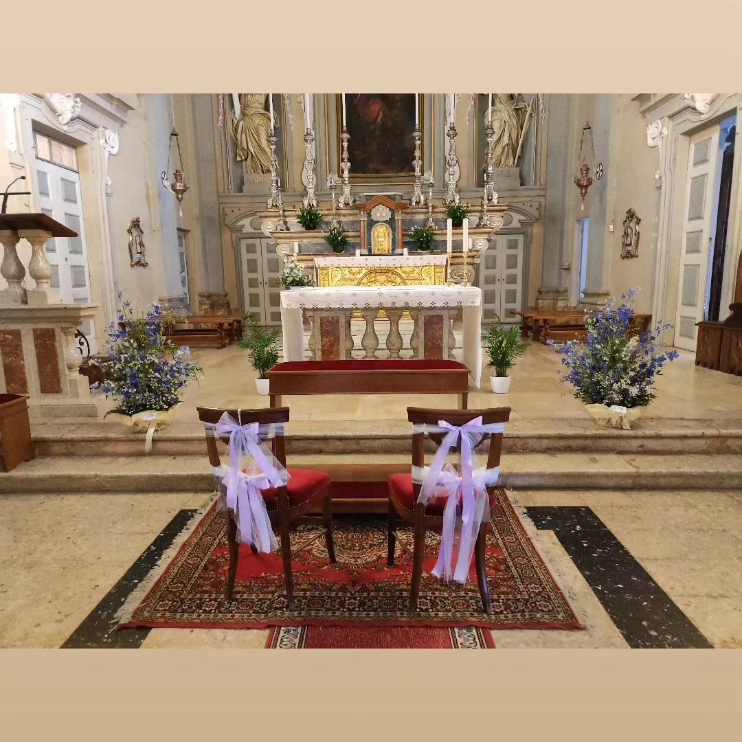 Un paio di sedie in una chiesa decorate con nastri viola e fiori.