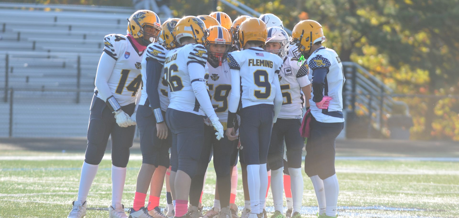 Football player in silver uniform runs with ball on a green field.
