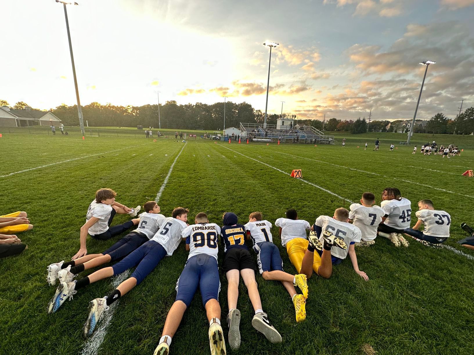 Football player holding a football on a green field at a stadium at night.