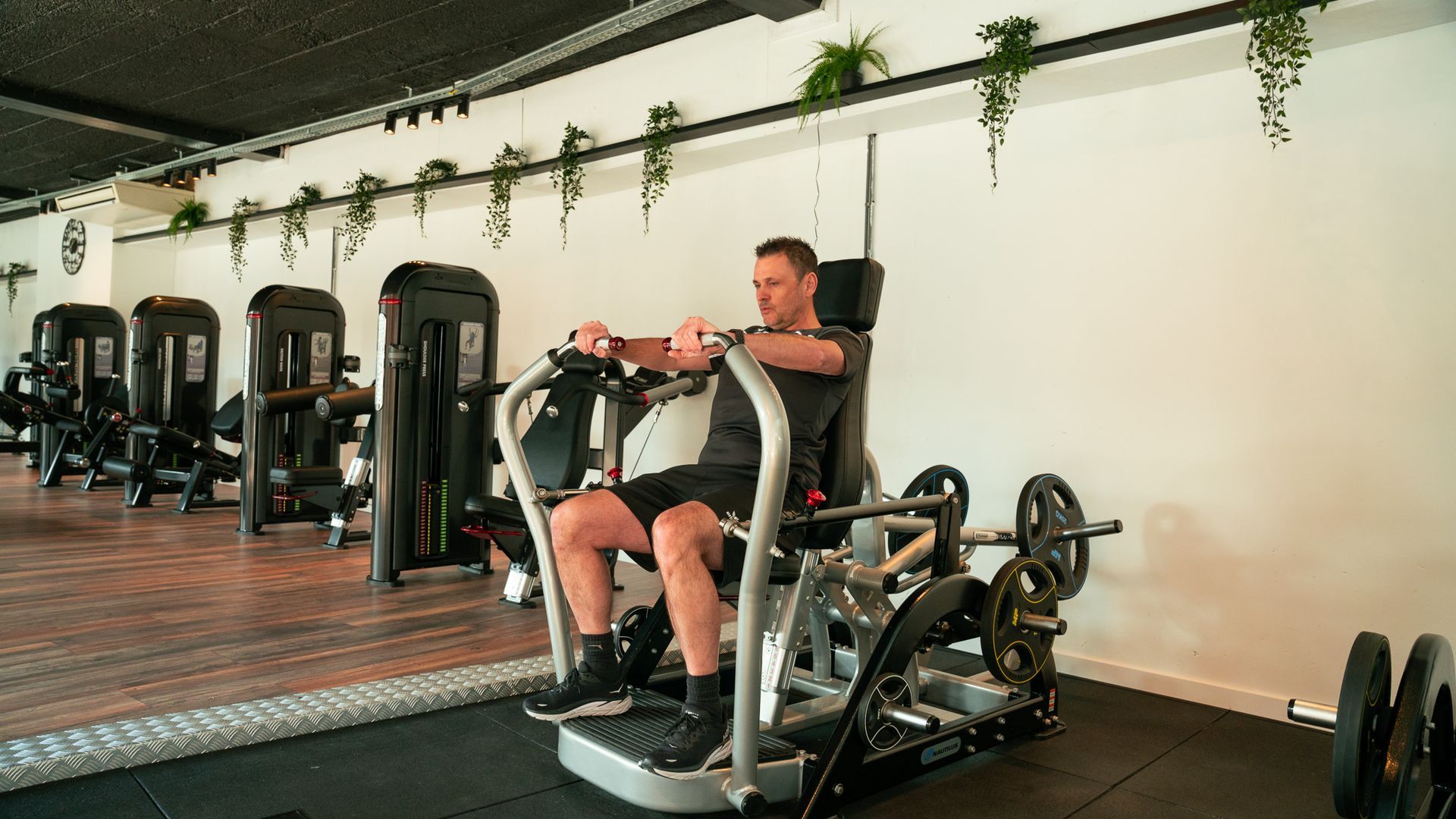 Een man zit op een apparaat in een sportschool.