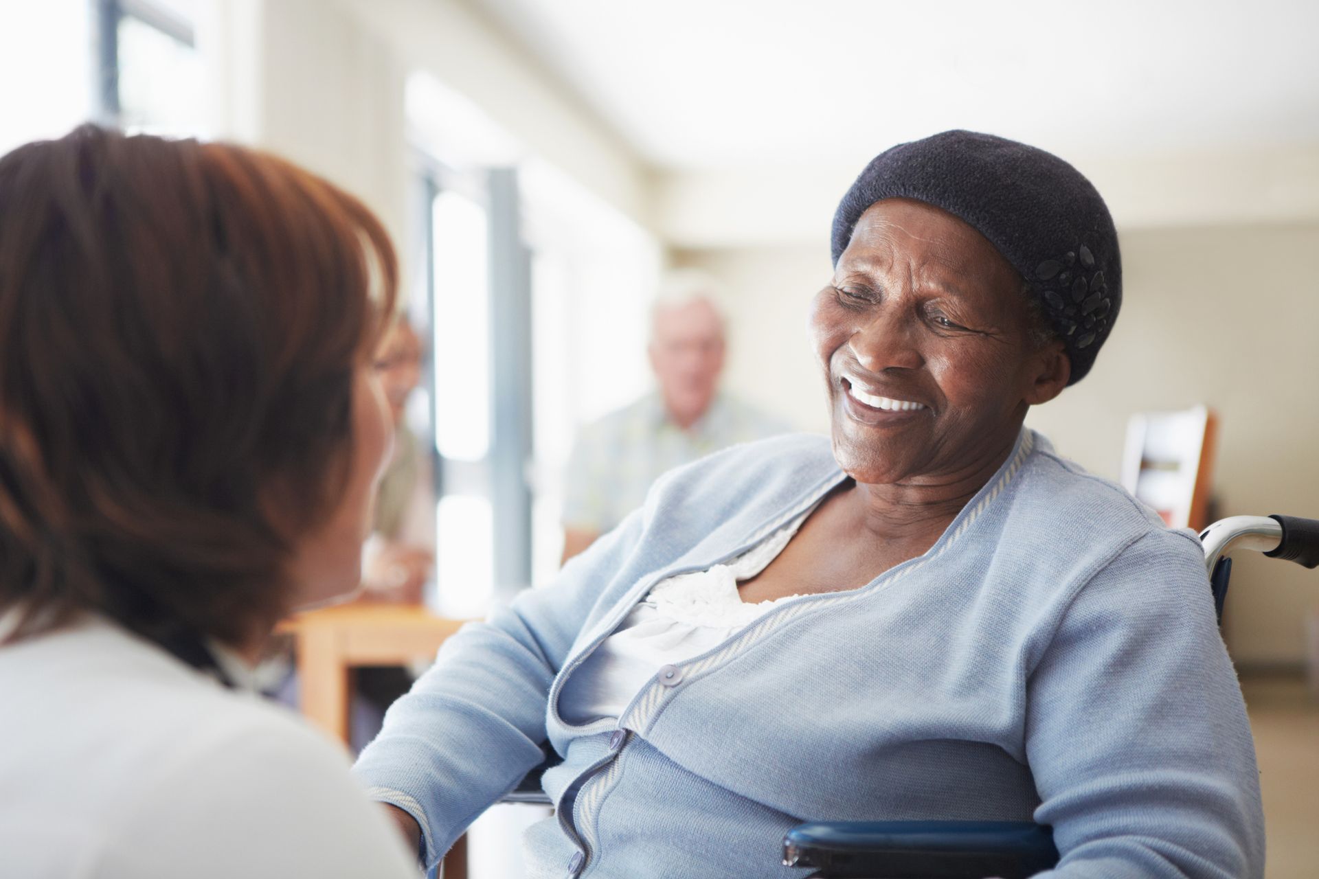 A nurse is serving an elderly woman at a table in a nursing home.