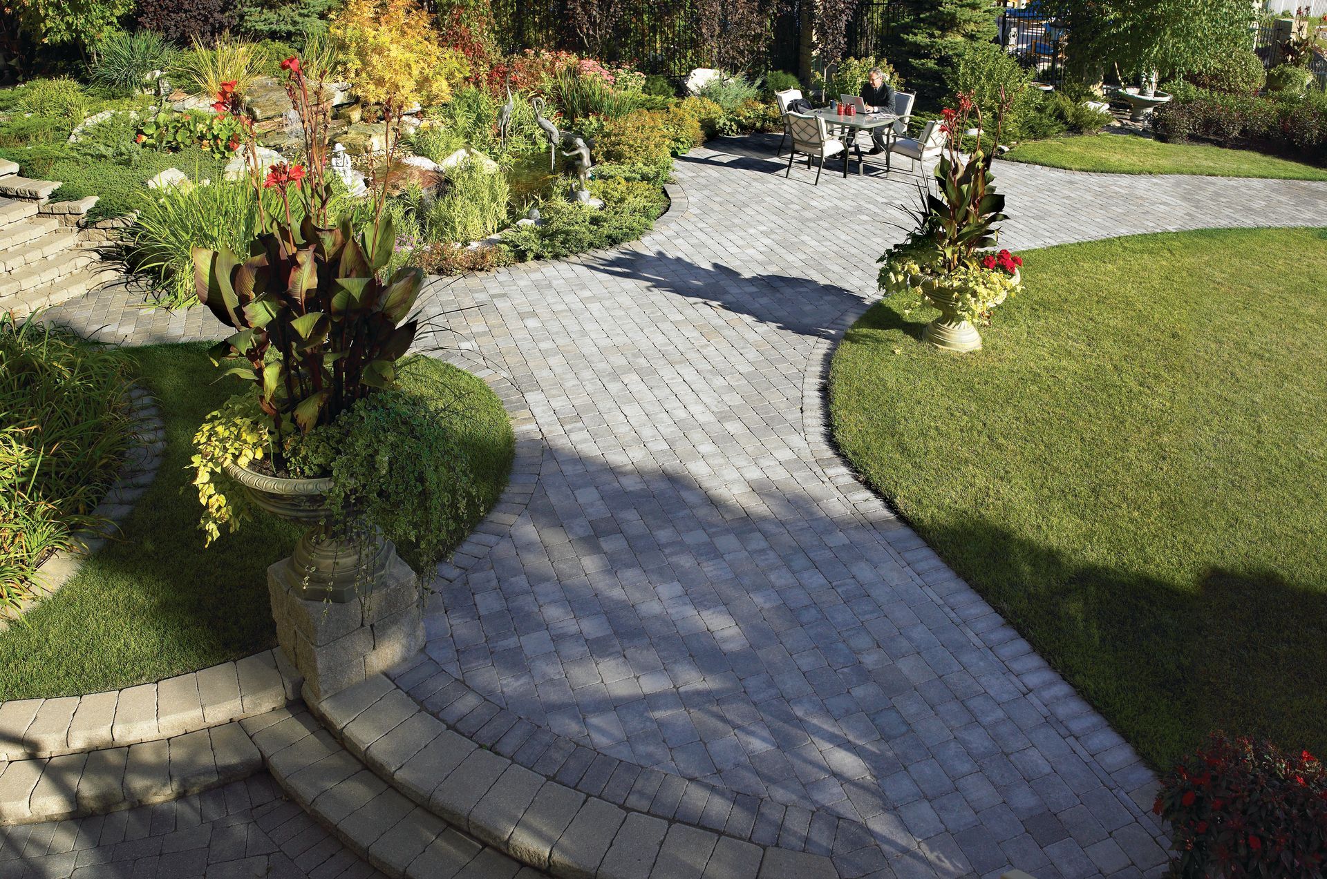 A brick walkway going through a lush green garden