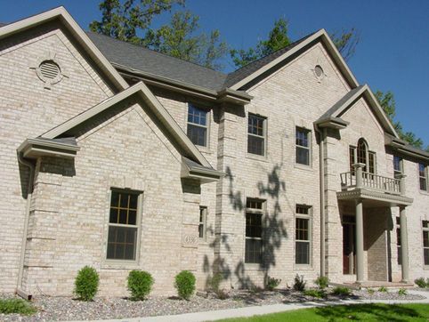 A large brick house with many windows and a balcony