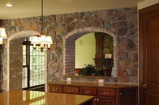 A kitchen with a stone wall and a large island