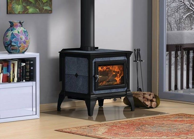 A blue wood stove is sitting on a tiled floor in a living room.