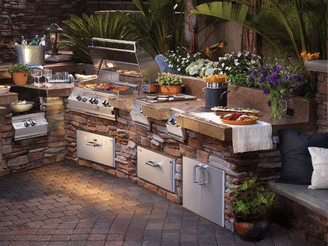 An outdoor kitchen with a brick wall and a grill