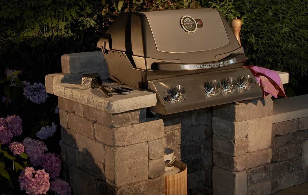 A grill is sitting on top of a brick wall.