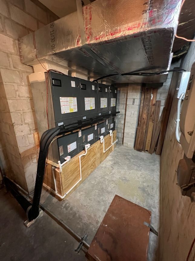A man in a red shirt is working on an air conditioner.
