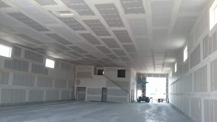 A large empty building with a lot of drywall on the walls and ceiling.