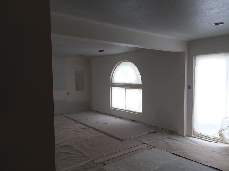 An empty room with a large window and a sliding glass door.