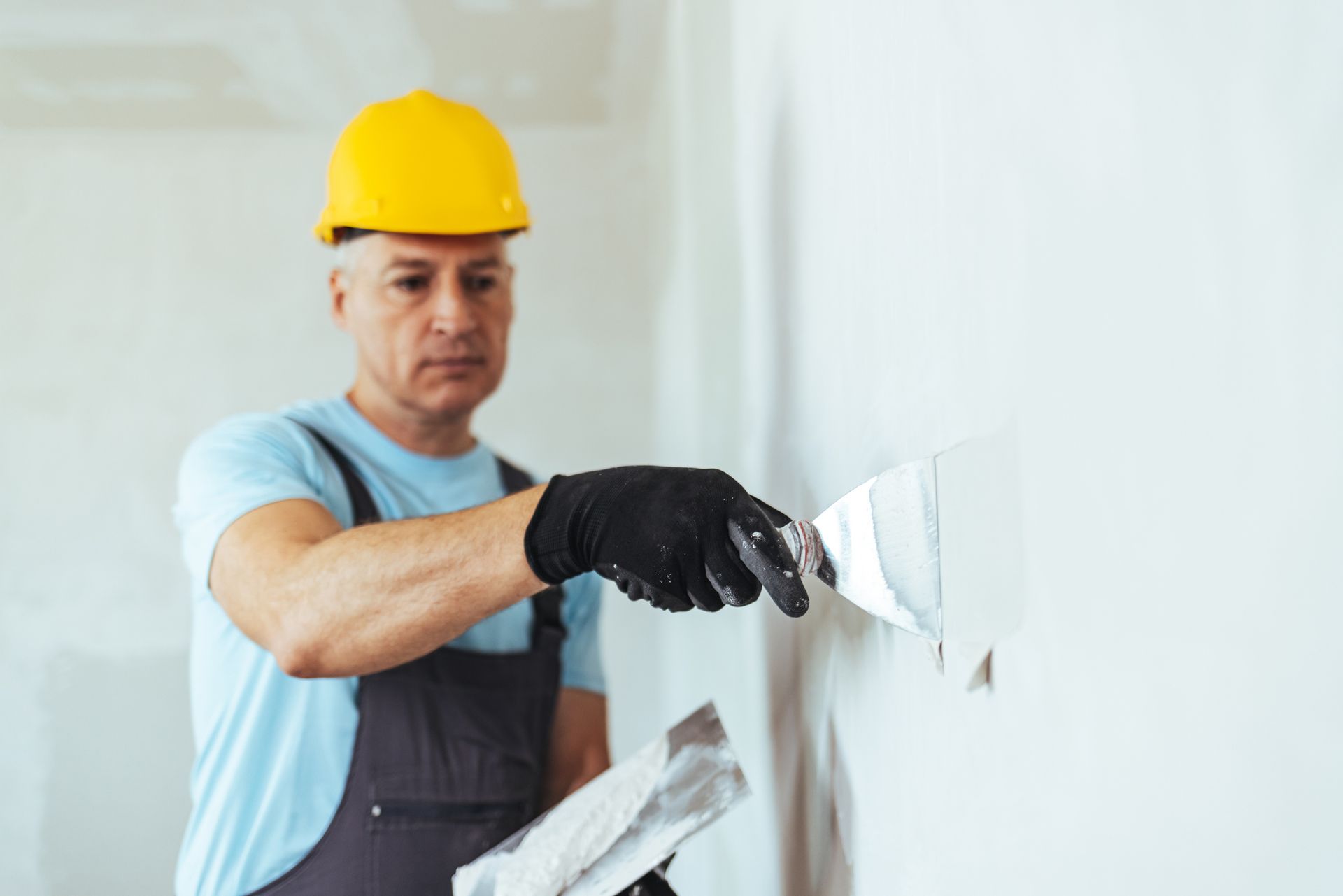 A man is plastering a wall with a spatula.