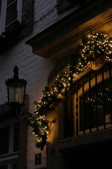 Christmas lights and garland adorn a doorway in a stone building at night.