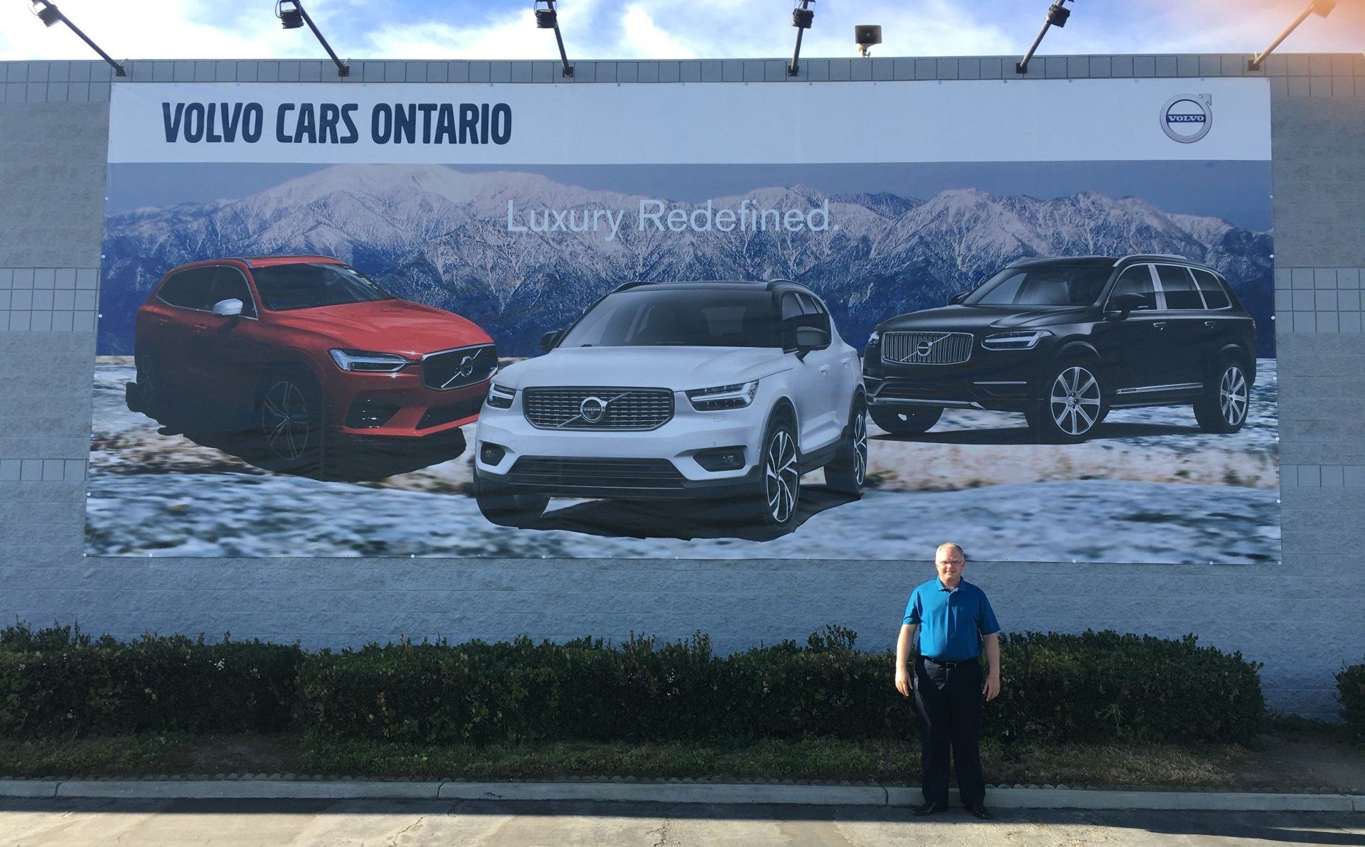A man is standing in front of a billboard for volvo cars ontario