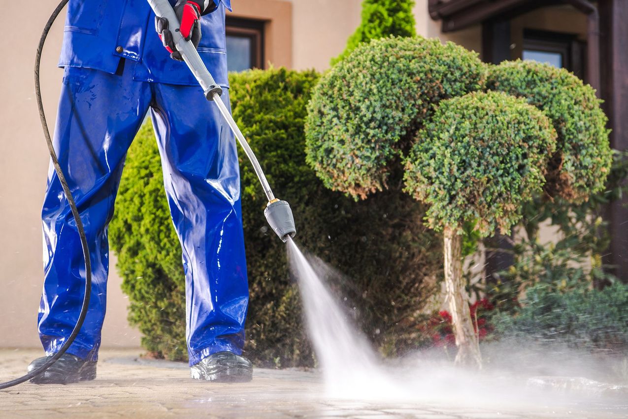 A man is using a high pressure washer to clean a sidewalk