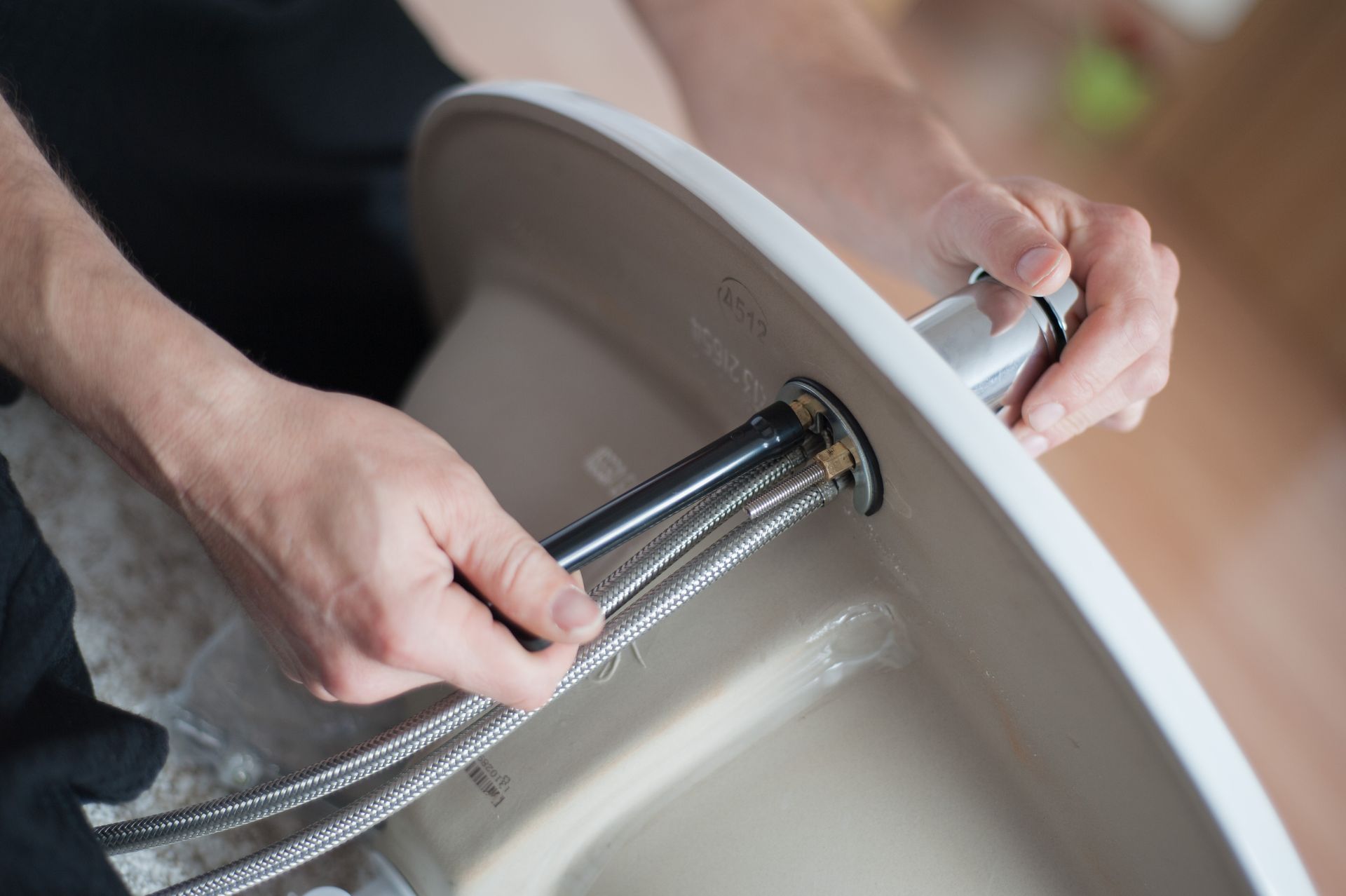 A person is fixing a sink with a hose.
