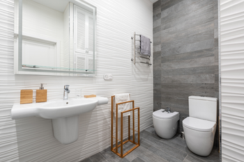 A bathroom with a sink , toilet , bidet and mirror.